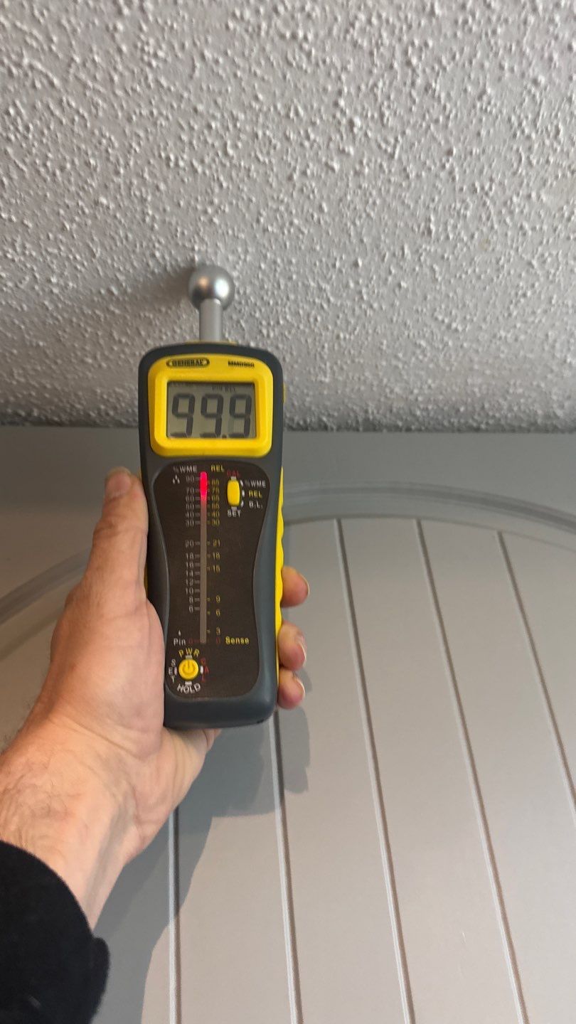 Moisture meter reading the damaged ceiling